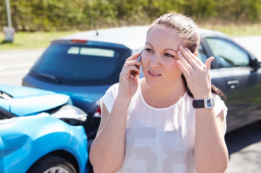Female driver calling police to report car accident.